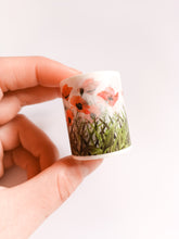 Load image into Gallery viewer, A hand holding a small cup with a Poppy FieldWashi Tape, 40mm Wildflower Decorative Tape design on it by GretelCreates.