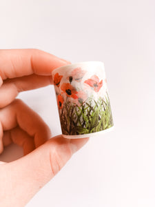 A hand holding a small cup with a Poppy FieldWashi Tape, 40mm Wildflower Decorative Tape design on it by GretelCreates.