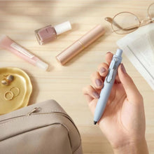 Load image into Gallery viewer, A woman is holding a Uni-Ball One P - Pocket Pen in Various Colours and a bag on a table.