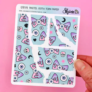 A person is holding a Shine Sticker Studio Pastel Goth Torn Paper Stickers with a pink and blue pattern on it.